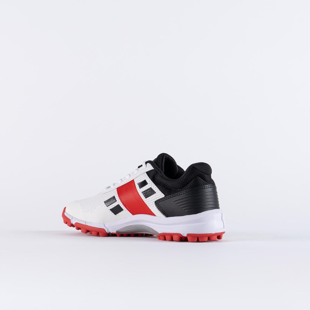 White sports shoe with black and red accents on a light gray Gray Nicolls Velocity 4.0 cricket footwear with EVA cushioning midsole