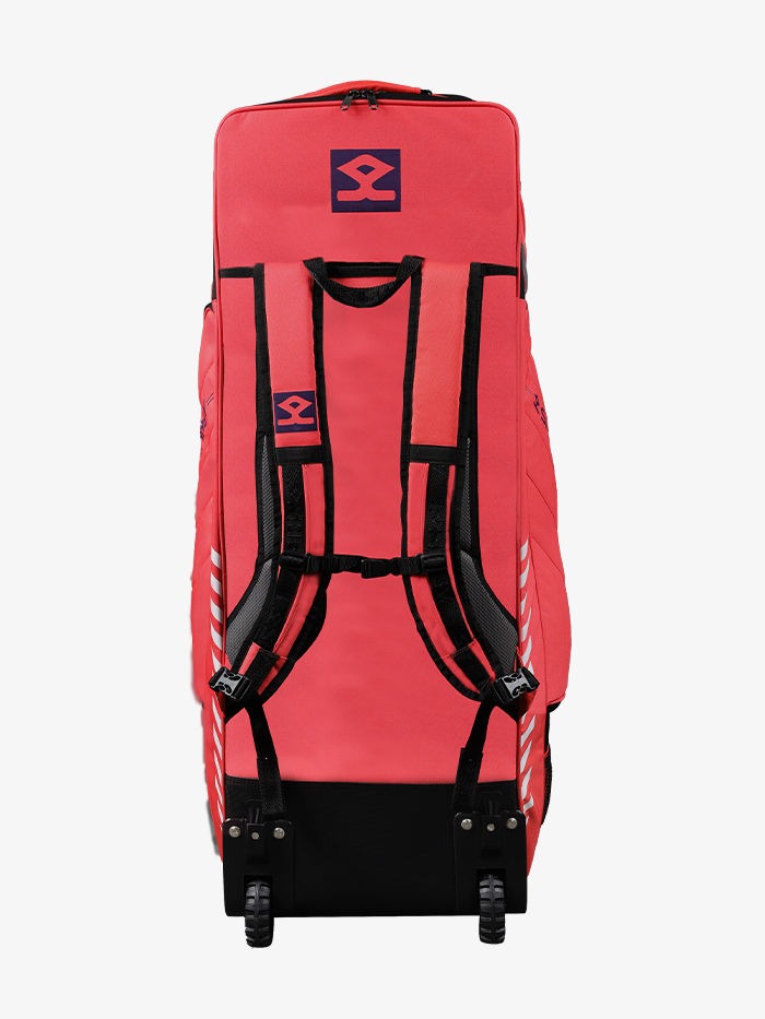 A red Shrey Legacy Duffle 120 Wheelie Cricket Kit Bag with black straps and wheels, designed for carrying cricket gear. Shrey Legacy Duffle 120 wheelie cricket kit bag with wheels, front view